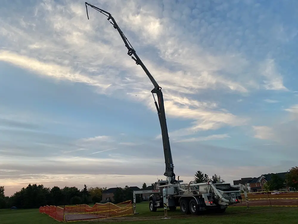 A far away shot of a concrete boom pump truck with the boom arm extended high.